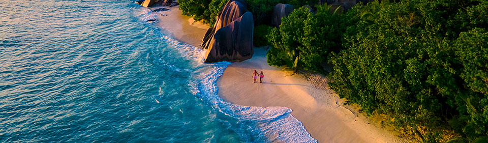 Distance view from above of a couple walking on a remote tropical beach during sunset.