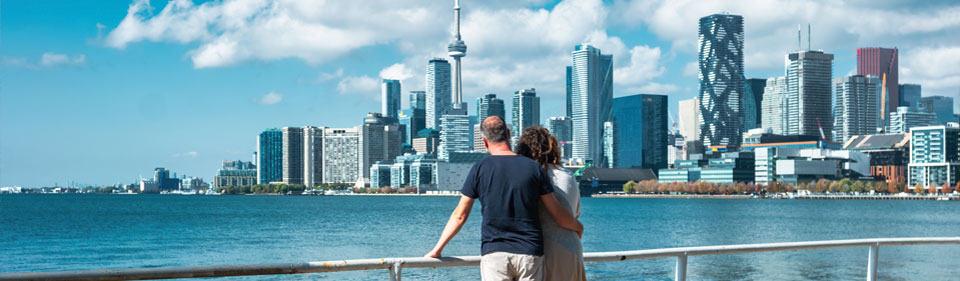 Couple standing together at a railing overlooking lake Ontario and the Toronto skyline.